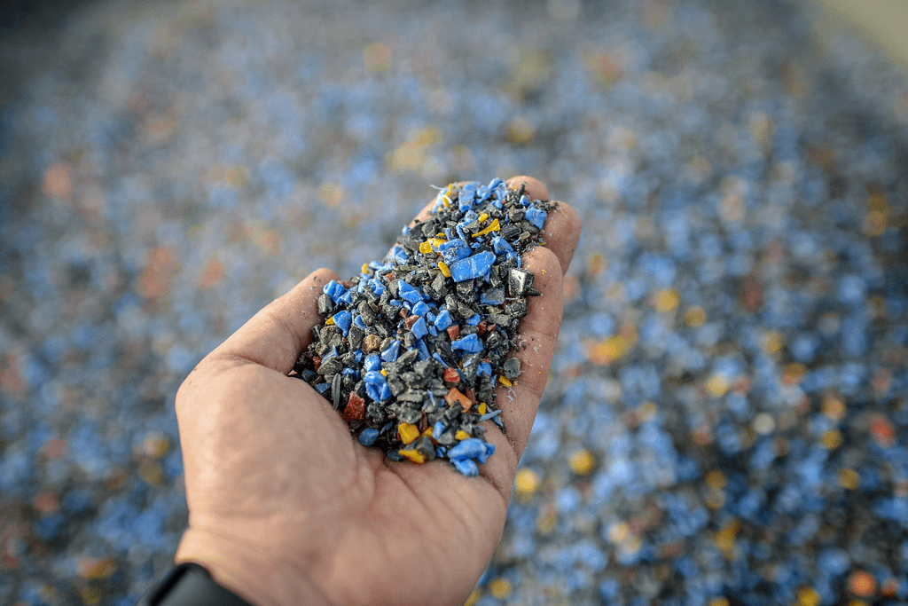 Granuli di plastica riciclata colorata tenuti in una mano.