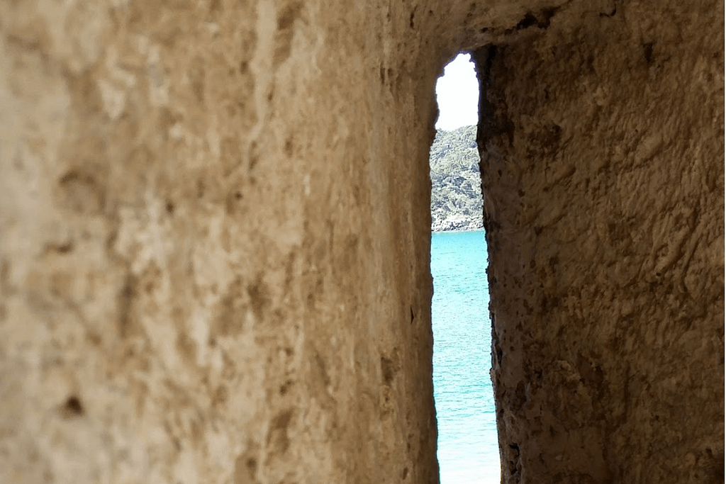 Dettaglio di una finestra in pietra con vista sul mare delle Isole Tremiti, simbolo di un'isola plastic free.