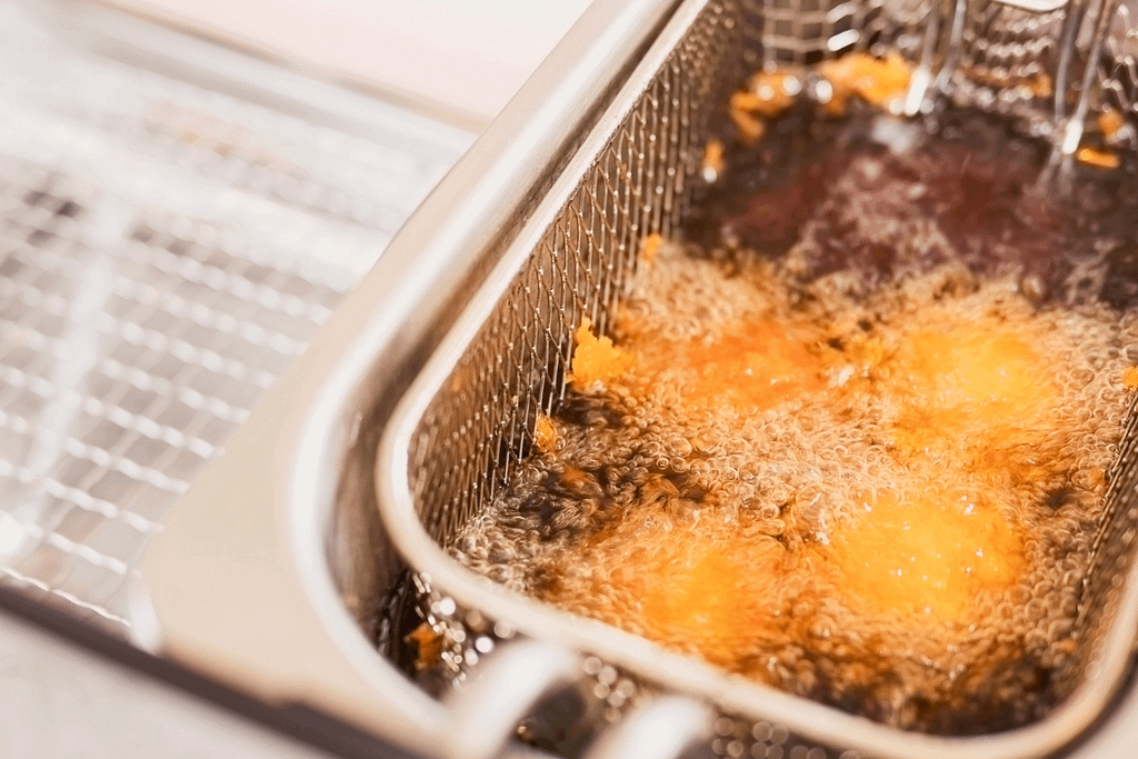 Olio esausto in friggitrice con residui di frittura