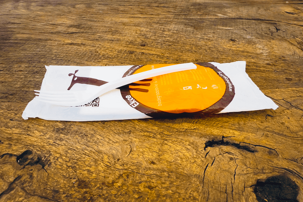 Kit di posate compostabili imbustate Ekoe su superficie in legno