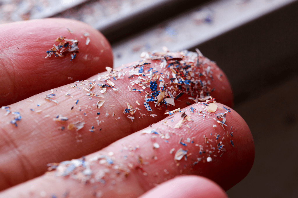 Microplastiche colorate sulla mano, esempio di materiale non biodegradabile.