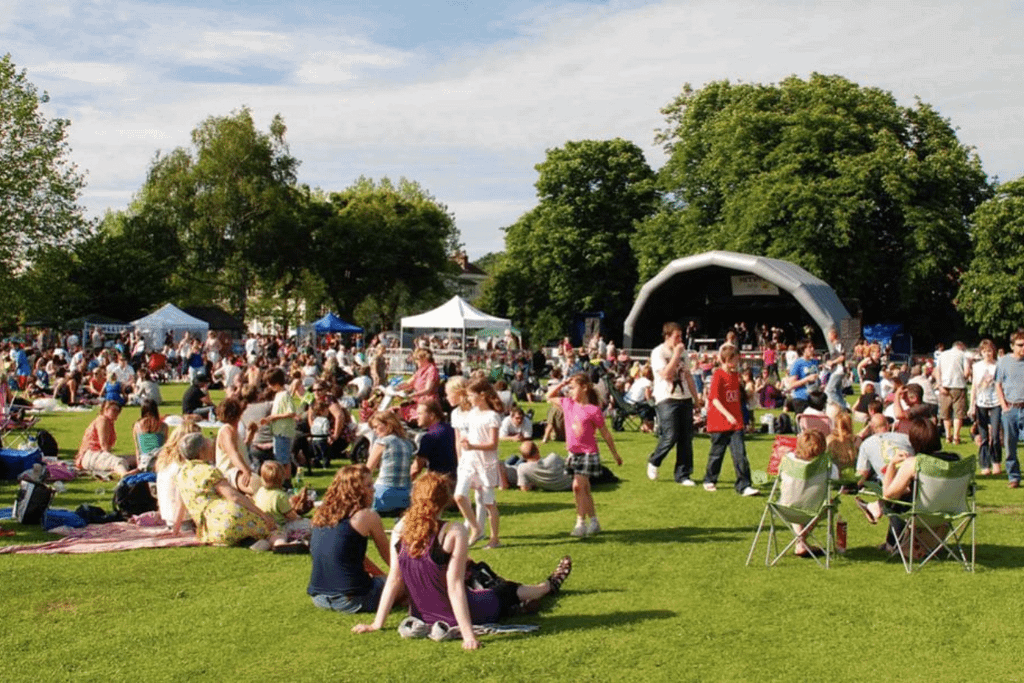 Persone a un evento all’aperto in un parco con palco e aree verdi